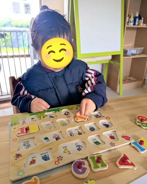 A child fitting letters into a wooden alphabet puzzle board