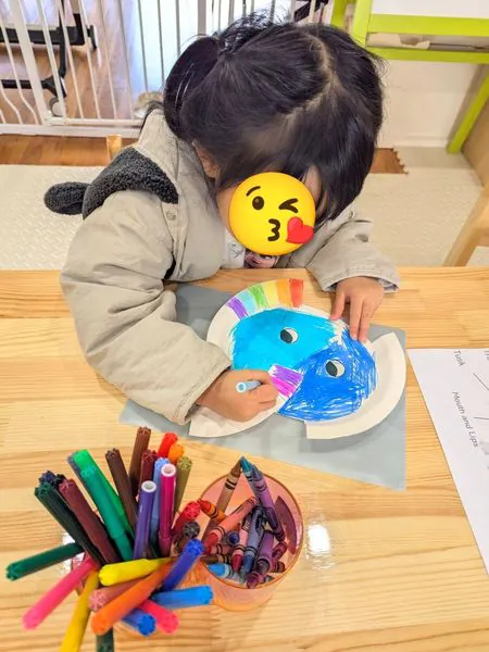 A child colouring a paper plate elephant