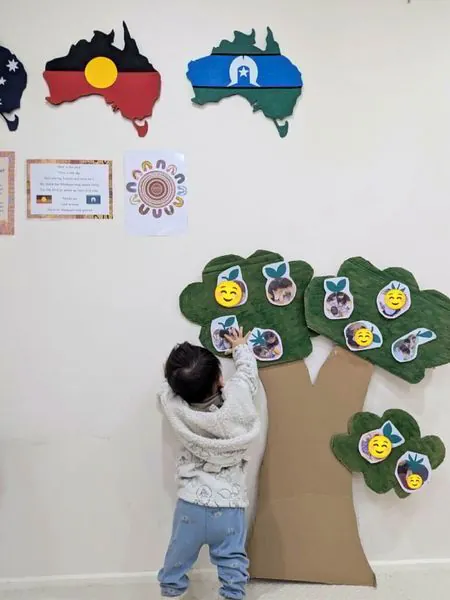 A child adding to the Our Community family tree on the wall