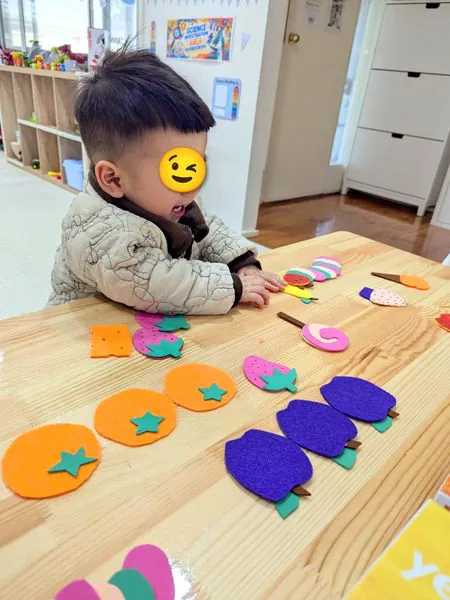 A toddler arranging felt fruit shapes