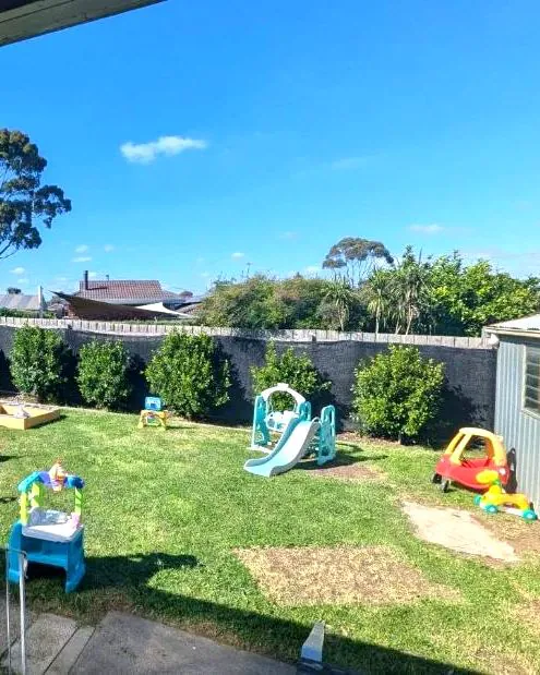 A grassy backyard with slides and outdoor play equipment