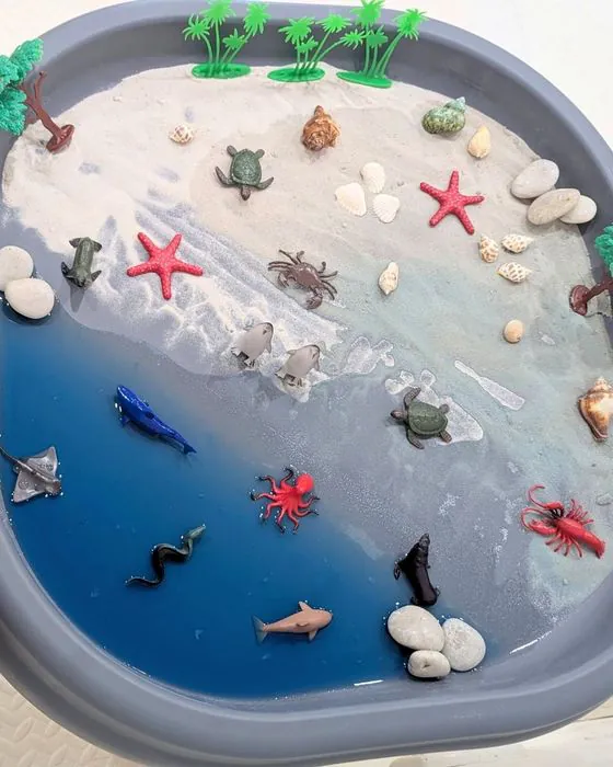 An ocean-themed sensory tray with sand, water and sea creatures